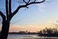 Skyline of a town seen from the distance over a lake at sunset framed by trees