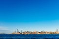 Skyline of uptown Manhattan over Hudson River under blue sky, at