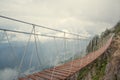 Skypark. An extreme, wooden rope suspension bridge over the chasm between two mountain peaks. Around the cloud. Sunny Royalty Free Stock Photo