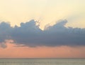 Skyscape at time of Sunset - Crepuscular Bright Sunrays spreading through Clouds with Orange sky at Horizon over Blue Sea Water Royalty Free Stock Photo