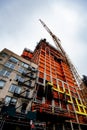 Skyscraper construction under way with cranes and orange tarp