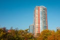 Skyscraper or flat block building on clear blue sky and autumn trees background. Closeup view with copy space. Modern urban Royalty Free Stock Photo