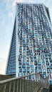A skyscraper of a futuristic shape against a blue sky. An example of modern architecture. Many windows are repeated in a pattern