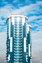 Skyscraper with a glass facade against a bright blue sky with figured clouds Royalty Free Stock Photo