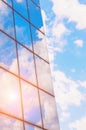 A skyscraper or modern building in a city with clouds and sunlight reflected in the Windows