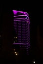 Skyscraper silhouette illuminated with magenta lines