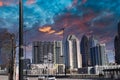 Skyscrapers and buildings in the city skyline with a tower crane and tall black light posts with blue and red sky Royalty Free Stock Photo