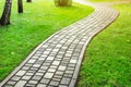 Slab stone paved path way along green grass lawn at park or backyard. Walkway footpath road at house yard garden Royalty Free Stock Photo