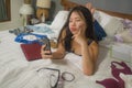 Slackness and disorganized during covid-19 home lockdown - young disorderly and chaotic Asian Chinese woman on bed using internet