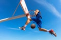 Slam Dunk. Side view of young basketball player making slam dunk