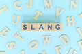 Slang in language concept. Wooden blocks typography word flat lay in blue background. Royalty Free Stock Photo