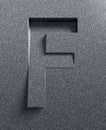 Slanted 3d font engraved and extruded from the surface, letter F