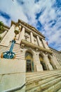 Slanted view of Steps leading into city hall gilded entrance with American flag over fancy doors