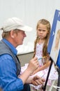 Slantsy, Leningrad region, Russia, July 30, 2016: Street painter drawing a cheerful portrait of a angry girl