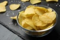 Slate board with bowl of potato chips on grey table, closeup Royalty Free Stock Photo