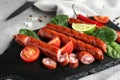 Slate board with delicious grilled sausages and vegetables on table, closeup Royalty Free Stock Photo