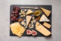 Slate board with different types of delicious cheese and snacks on grey table, top Royalty Free Stock Photo