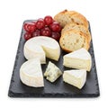 A slate cheese board featuring an assortment of cheeses, including two rounds of Royalty Free Stock Photo