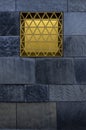 Slate facade with yellow luminous window with privacy screen and grid as burglary protection