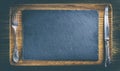 Slate flat plate, Cutlery. Wooden table. oak Board. Space for text, top view. Film camera effect Royalty Free Stock Photo