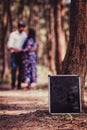 Slate in focus with couple standing in the background surrounded by trees