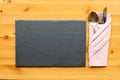 Slate place mat and cutlery in folded napkin