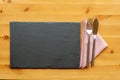 Slate place mat with fish knife and fork on top of a folded napkin