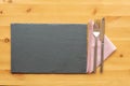 Slate place mat with knife and fork on top of a folded napkin