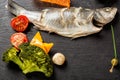 Slate plate of baked sea bass with tomatoes, broccoli, olive and sauce. Close up image Royalty Free Stock Photo