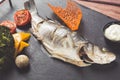 Slate plate of baked sea bass with tomatoes, broccoli and sauce. Close up image Royalty Free Stock Photo