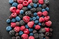 Slate plate with delicious frozen berries on dark textured background