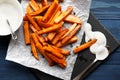 Slate plate with deliciously cooked sweet potatoes, rosemary, sauce and spices, herbs on a wooden Royalty Free Stock Photo