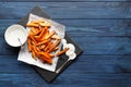 Slate plate with deliciously cooked sweet potatoes, rosemary, sauce and spices, herbs on a wooden Royalty Free Stock Photo