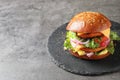 Slate plate with double vegetarian burger on grey background.