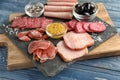 Slate plate with variety of delicious deli meats with spices on wooden board Royalty Free Stock Photo