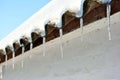 Slate roofs with icicles covered with snow, covered with snow, white wall background