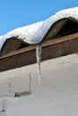 Slate roofs with icicles covered with snow, covered with snow, white wall background