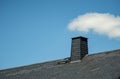 Slate tiled roof with chimney and blue sky