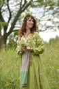 Woman in a green dress with a wreath of daisies in her hair and a bouquet of daisies in her hands Royalty Free Stock Photo