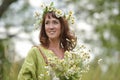 Woman in a green dress with a wreath of daisies in her hair and a bouquet of daisies in her hands Royalty Free Stock Photo