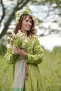 Woman in a green dress with a wreath of daisies in her hair and a bouquet of daisies in her hands Royalty Free Stock Photo