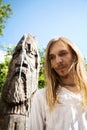 Slavic pagan young long-haired man next to a wooden pole idol sculpture Royalty Free Stock Photo