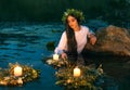 Slavic woman nymph stands in water herbal wreath floa candles burning. Fantasy girl mermaid. White long wet dress Royalty Free Stock Photo