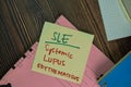 SLE - Systemic Lupus Erythematosus write on sticky notes isolated on Wooden Table