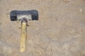 The sledgehammer is lying on the sand. A large hammer lies on the sandy surface