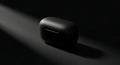 Sleek Black Earbud Case Emerging from Shadows in a Dramatic Diagonal Spotlight Royalty Free Stock Photo