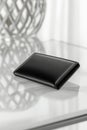 Sleek black leather wallet on glass table with subtle geometric background Royalty Free Stock Photo