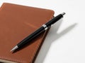Black pen on brown leather notebook isolated on white background Royalty Free Stock Photo
