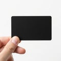 A sleek black rectangular card held by a hand against a plain background Royalty Free Stock Photo