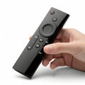 A sleek black smart remote control being held by a hand against a plain background Royalty Free Stock Photo